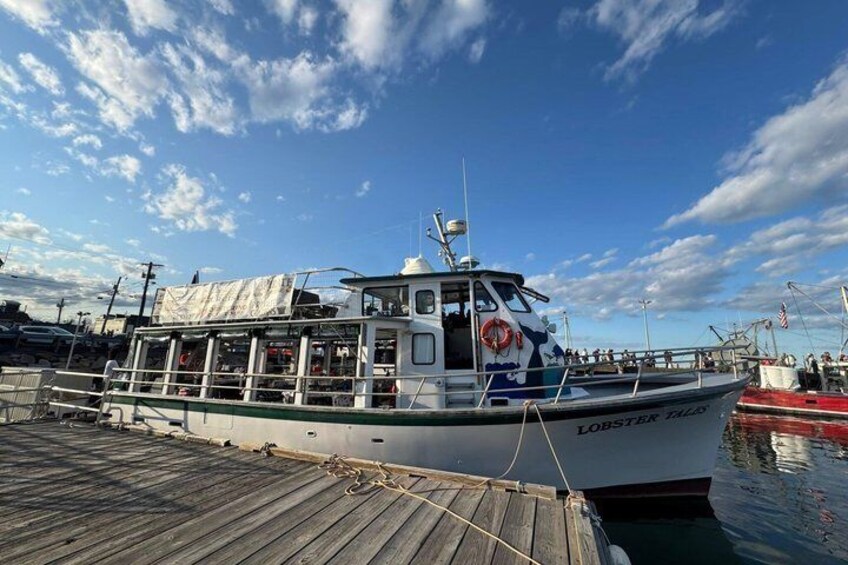 A white boat named 'Lobster Tail' docked at a pier with a clear sky. 2