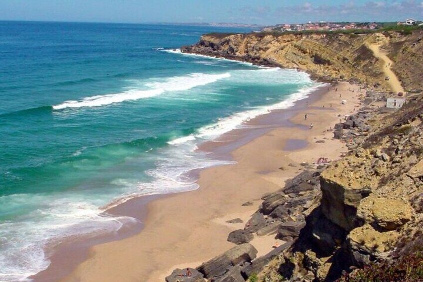 A coastal landscape with a sandy beach, rocky cliffs, and the ocean. 4