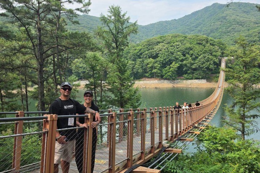 Un pont suspendu enjambant une rivière, entouré de collines boisées. 1