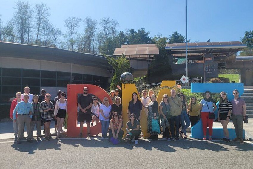 Eine Gruppe von Menschen steht vor einem Gebäude mit einer großen 'D'-Struktur. 3