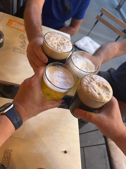 Four hands holding glasses of beer, with a watch on one wrist. 2