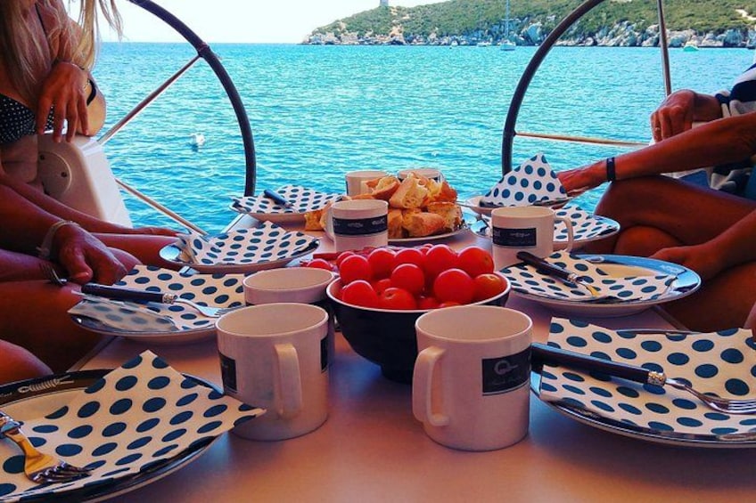 Un barco con gente cenando, un tazón de tomates y una vista panorámica del mar. 3