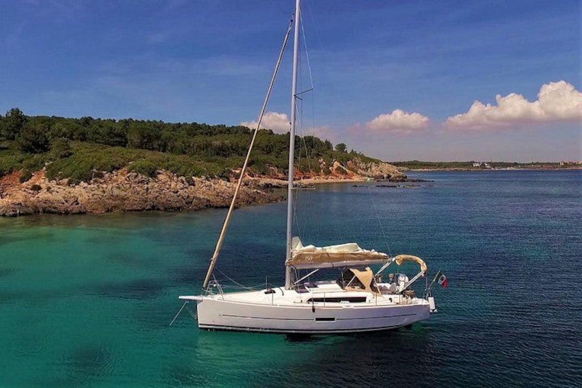 Un velero anclado cerca de una costa rocosa con agua turquesa cristalina. 4