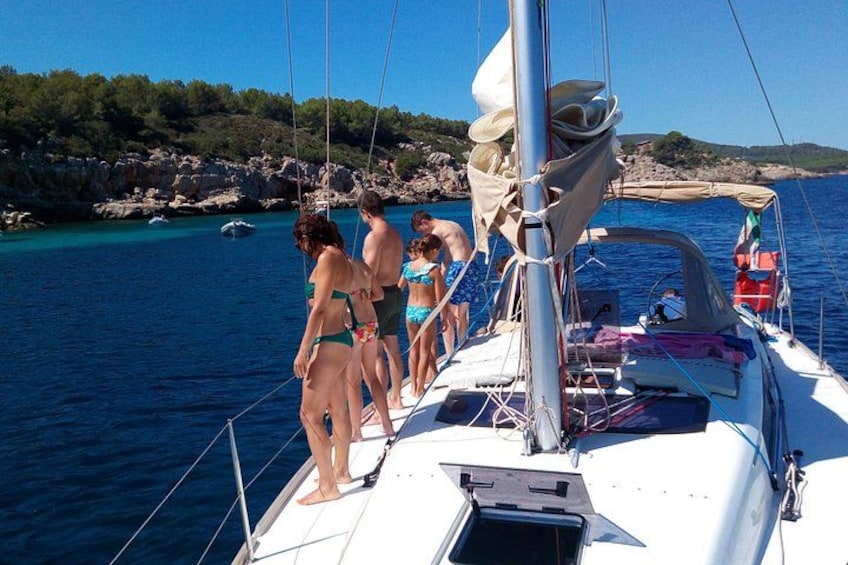 Un velero con personas en la cubierta, mar tranquilo, costa rocosa y cielo despejado. 5