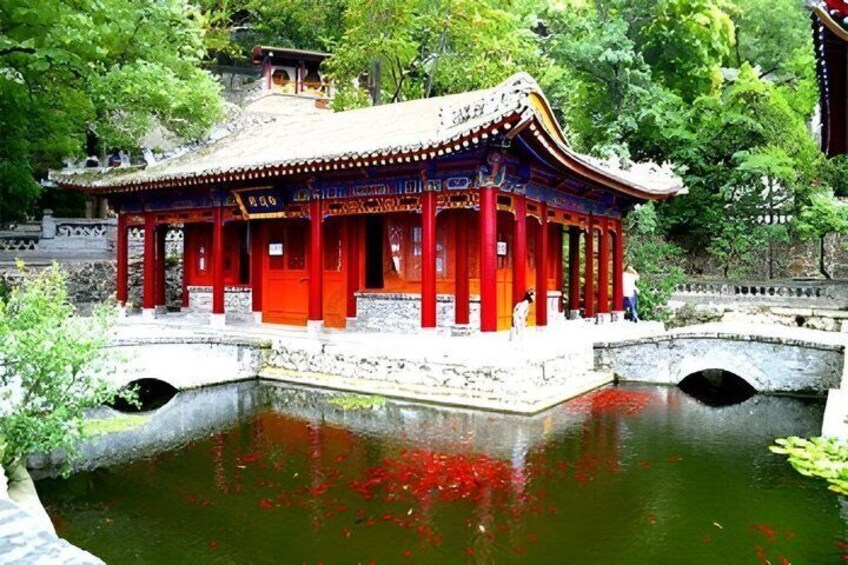 A traditional red pavilion by a pond with a stone bridge. 5