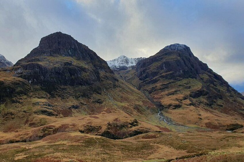 A mountainous landscape with two prominent peaks, a valley, and a river flowing through. 3