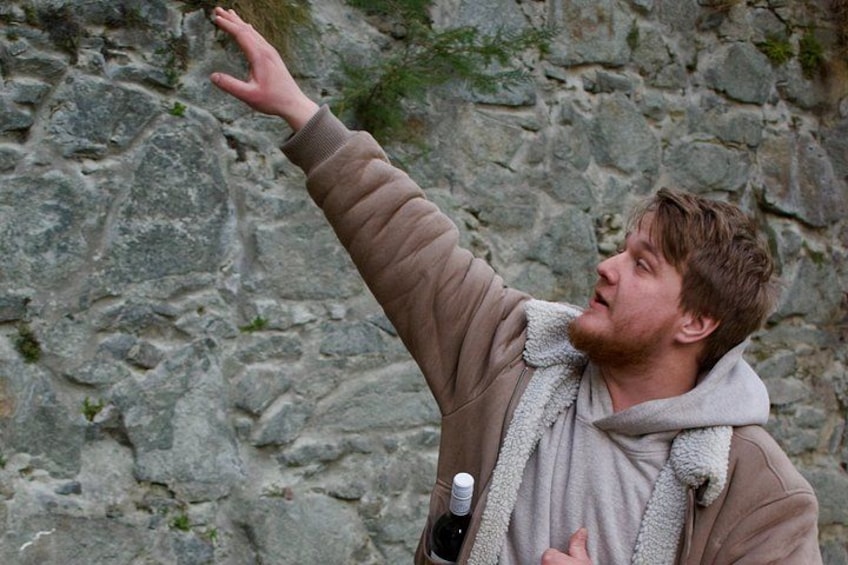Une personne portant une veste marron et une écharpe grise, tendant la main vers une falaise rocheuse. 4