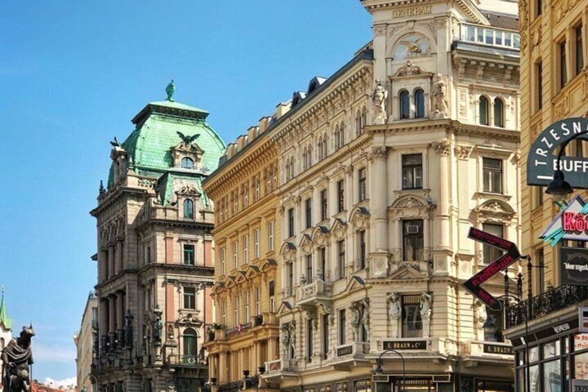 A historic building with ornate architecture, a green dome, and a sign for 'Kooperativa Bank.' 4