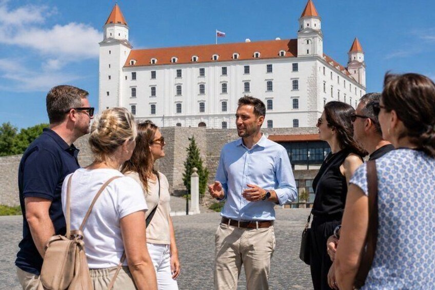 A group of people standing in front of a historic building with a red roof and white walls. 2