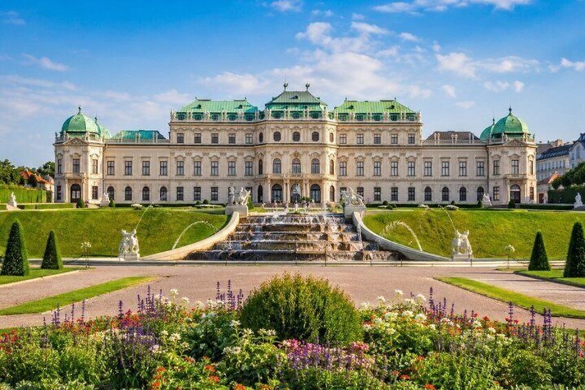 A grand palace with a large fountain, manicured gardens, and distinctive green domes. 1