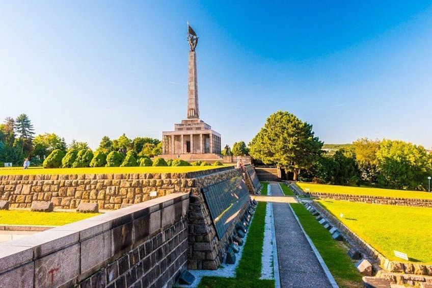 Un monumento con un obelisco alto, rodeado de un muro de piedra y un sendero. 2