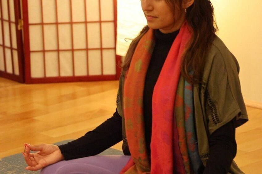 A person sitting on a mat in a room with wooden flooring and a traditional Japanese sliding door in the background. 3