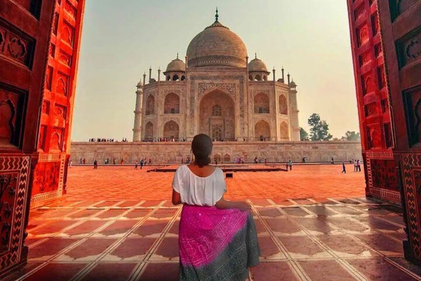 A person sitting on a patterned floor, facing the Taj Mahal. 2