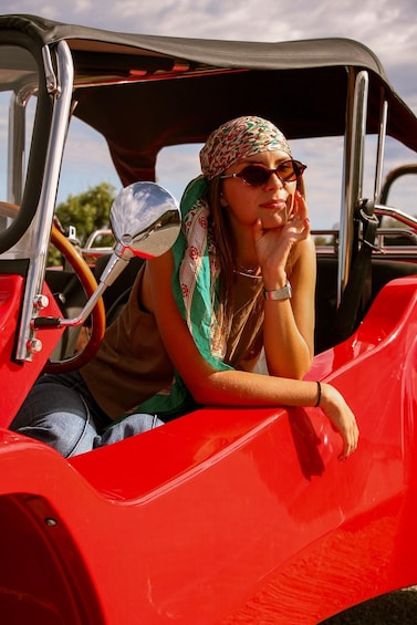 A person in a red vintage car with a hood open. 5