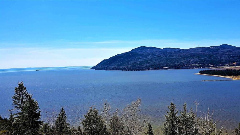 A calm lake with mountains in the background and coniferous trees in the foreground. 5