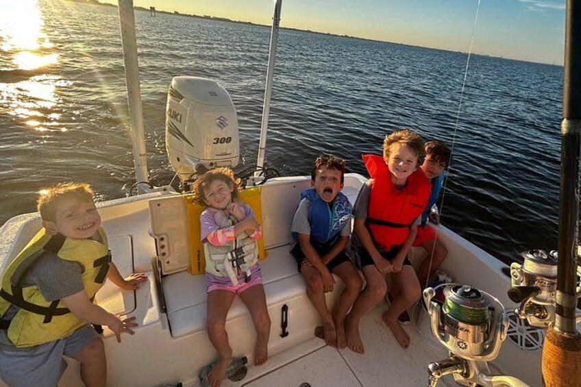 A boat with four people wearing life jackets, a fishing rod, and a water bottle. 5