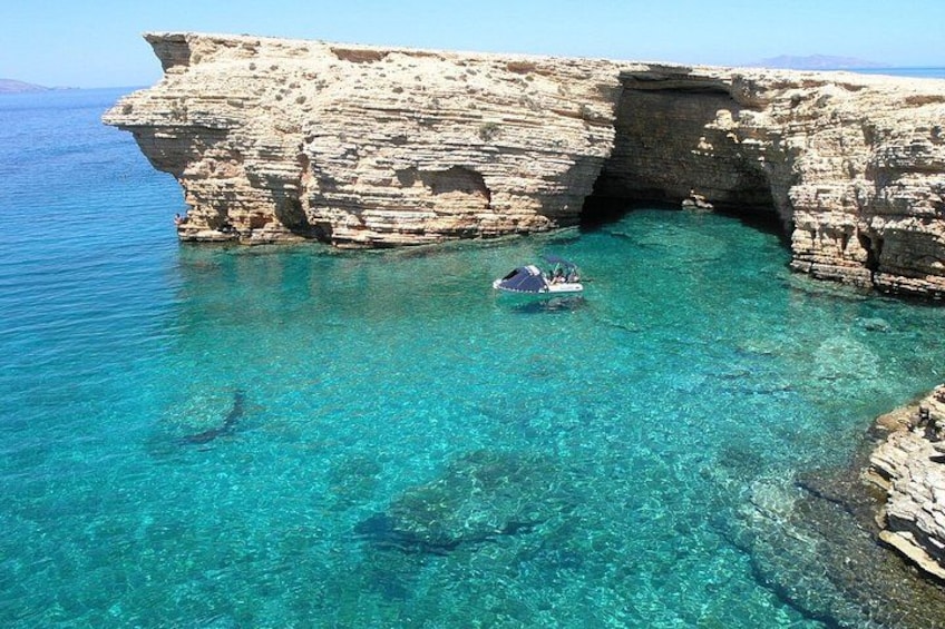 A boat in a clear blue sea with rocky cliffs. 4