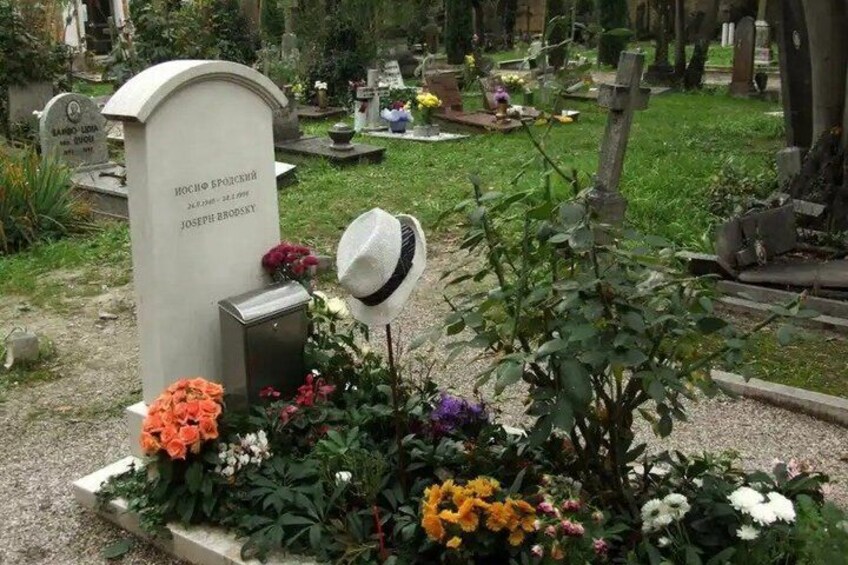 A cemetery with gravestones, flowers, and a hat on a gravestone. 2