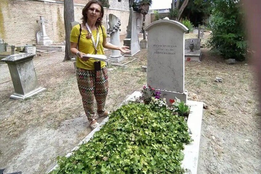A person standing next to a gravestone in a cemetery with greenery around. 1