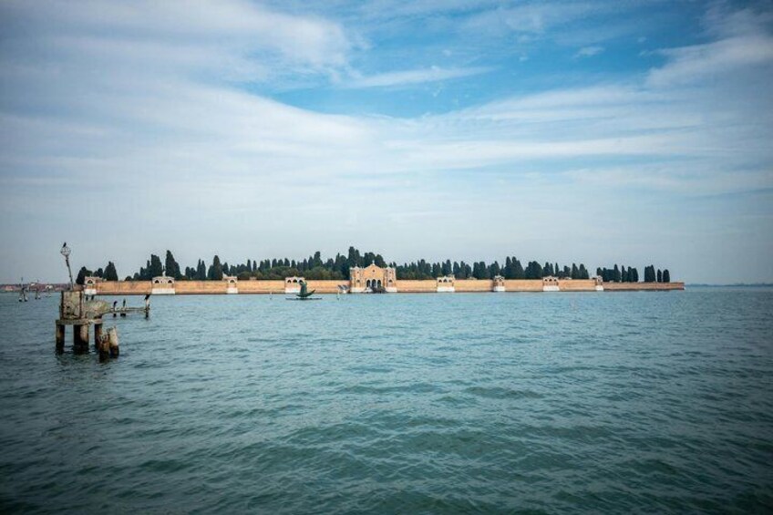 A calm body of water with a distant shoreline featuring a fortified structure and trees. 5