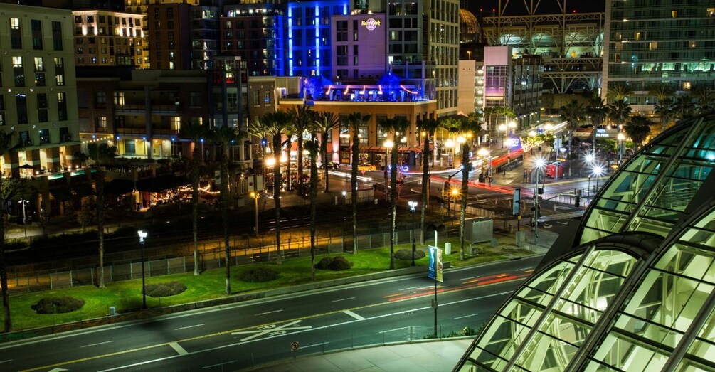 A cityscape at night with illuminated buildings, a busy street, and palm trees. 2
