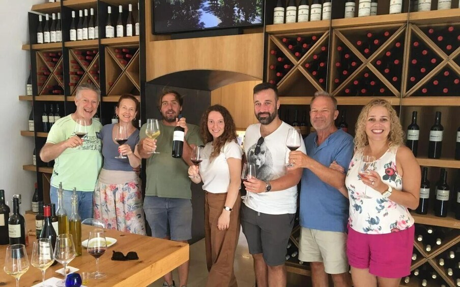 A group of people standing in a wine cellar holding wine glasses. 2