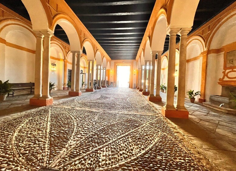 A corridor with arches, patterned floor, and columns. 5