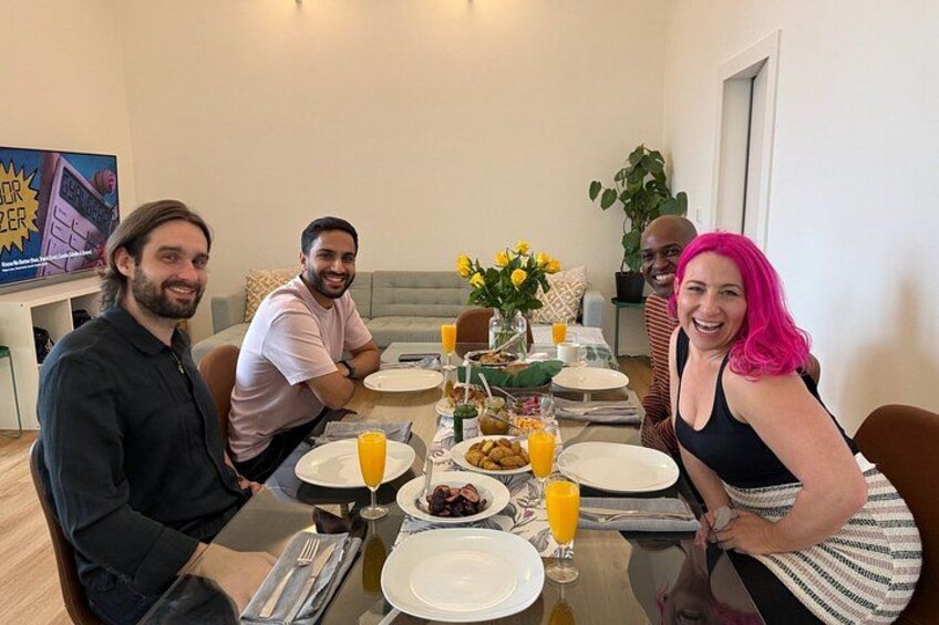 A group of people sitting around a table with food and drinks. 4