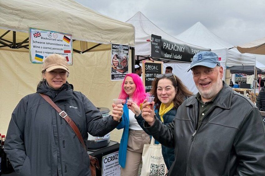 People at an outdoor market with tents and signs in the background. 5