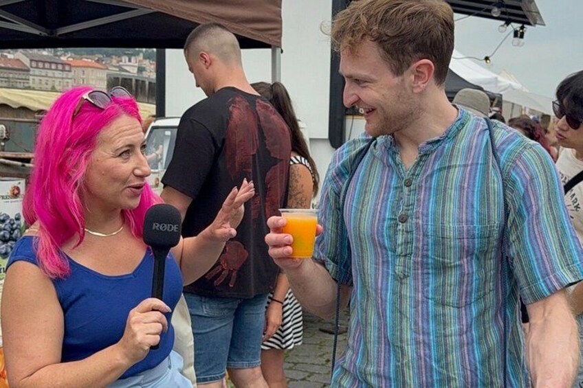 Two people conversing, one holding a microphone and the other holding a drink. 3