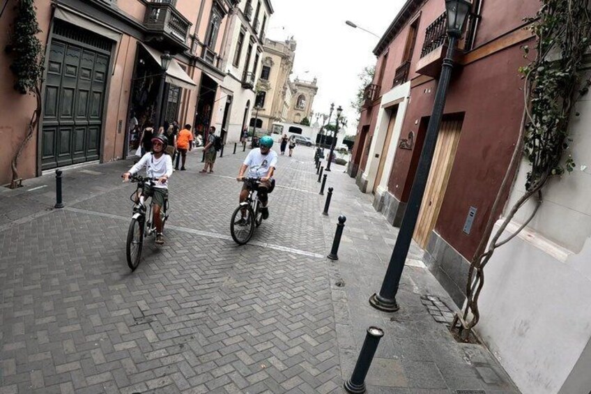 A cobblestone street with cyclists, historic buildings, and a clear sky. 5