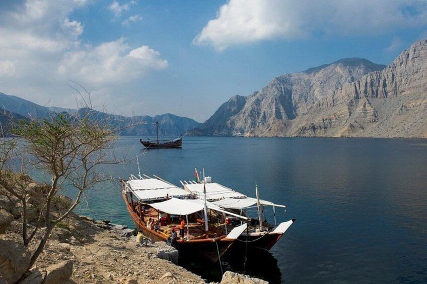 A boat docked at a rocky shore with mountains in the background. 3