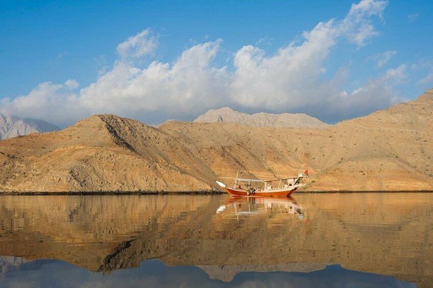 A boat on a calm body of water with a mountainous landscape in the background. 1