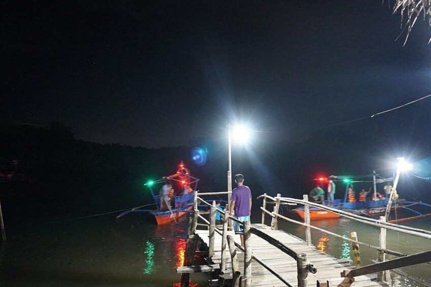 A nighttime scene with two illuminated boats docked at a pier. 3