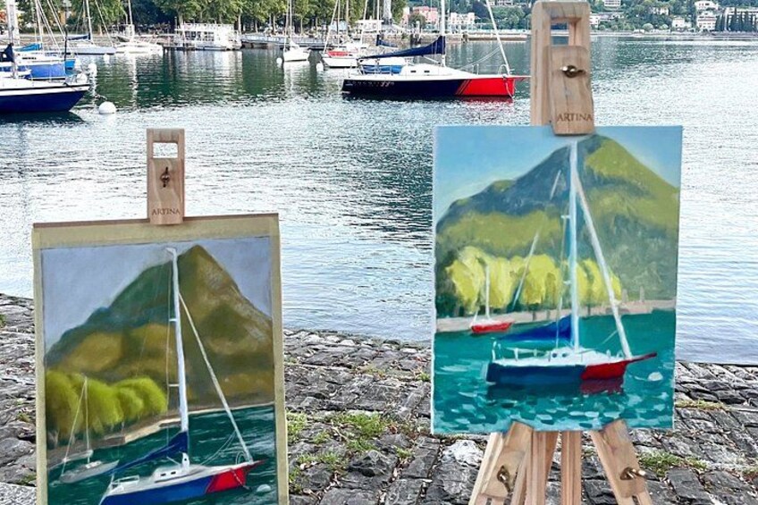 Two paintings on easels depicting sailboats on water with mountains in the background. 2