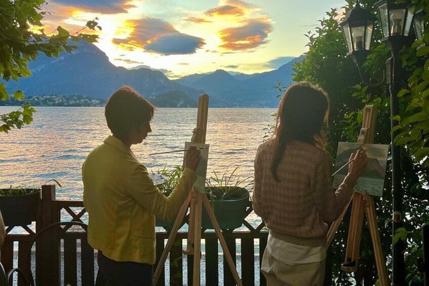 Two people painting a landscape with a lake and mountains in the background. 4