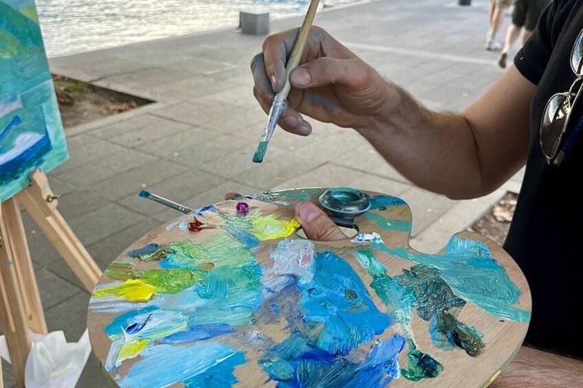 A person painting on a palette with various colors. 3