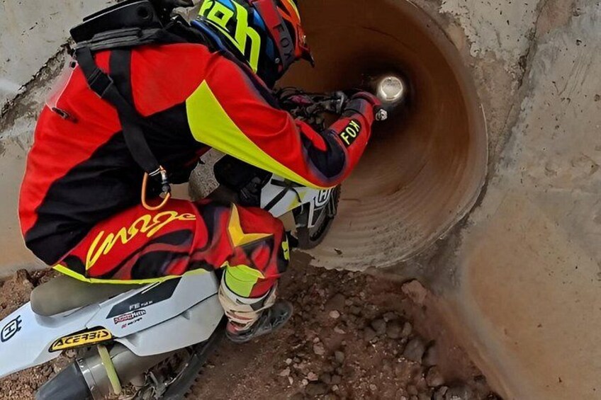 A person on a dirt bike navigating a narrow, rocky passage. 4