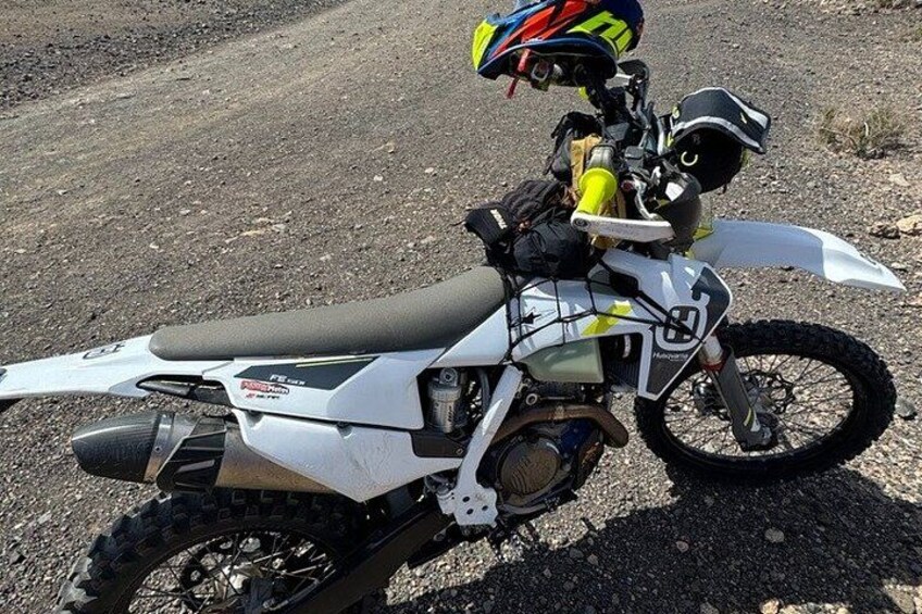 A dirt bike parked on a gravel surface. 2