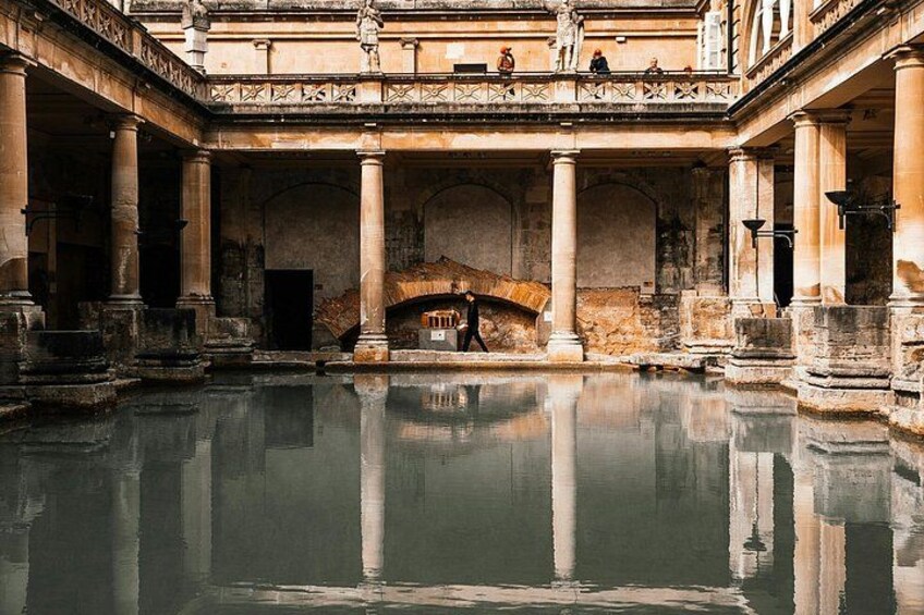 Un antiguo baño romano con una fuente central, columnas y arcos. 3