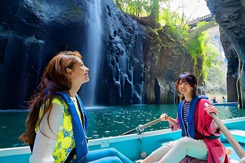 Two people in a boat on a calm river with a waterfall in the background. 1
