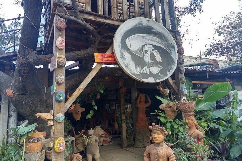 Una tienda rústica con varias esculturas y una gran placa de metal con un rostro. 2