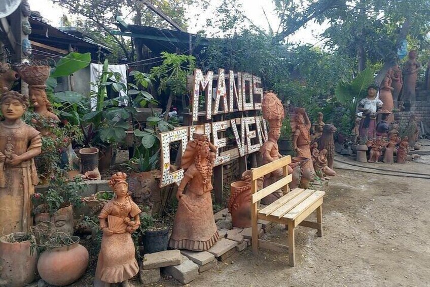 Terracotta statues, a wooden bench, and a sign that reads 'MANDALA EVENING'. 5