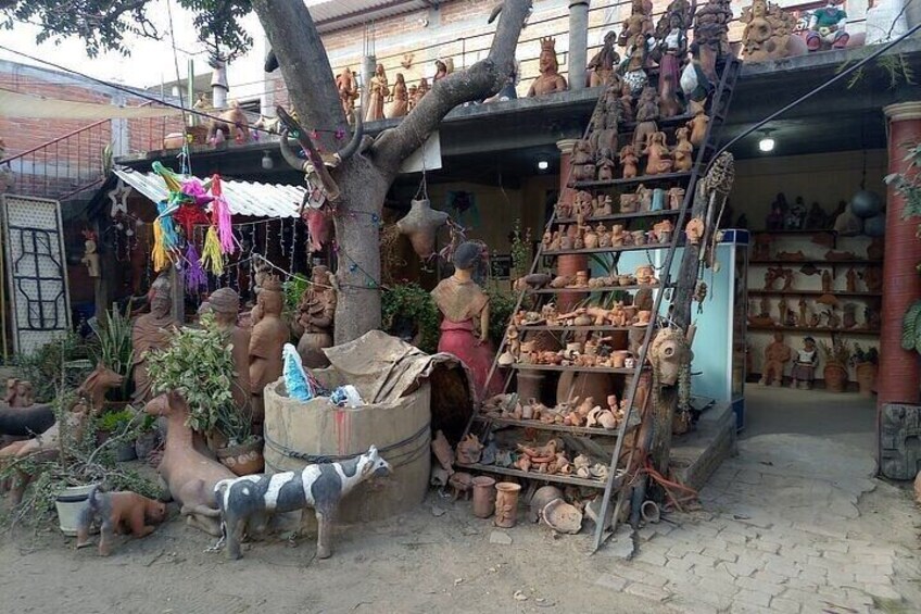 A pottery workshop with shelves of pottery, a tree, and a ladder. 4