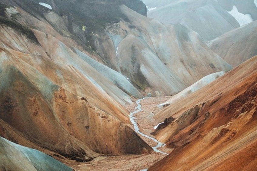 A rugged landscape with a narrow valley and steep, colorful rock formations. 4