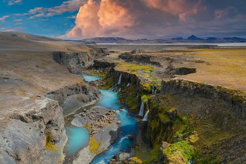 A river flowing through a rocky landscape with waterfalls and a dramatic sky. 2