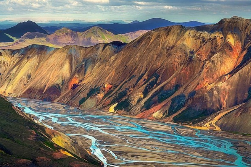 A river winding through a mountainous landscape with varying terrain and colors. 5