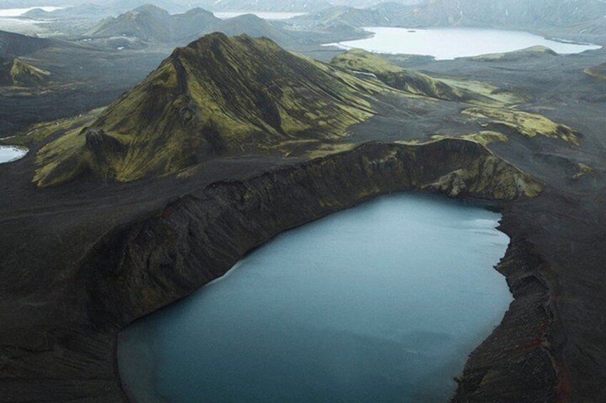 A volcanic landscape with a crater lake surrounded by rugged terrain. 3