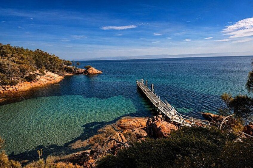 A coastal landscape with a pier extending into the sea, surrounded by rocky terrain and sparse vegetation. 1