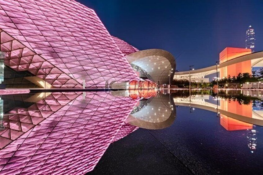 A pink architectural structure with a reflective surface, a bridge, and a building with a pointed roof. 5